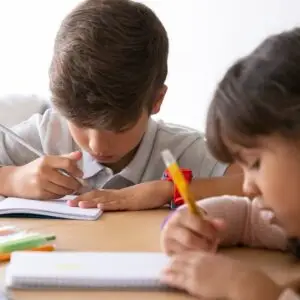 Two children studying together at home, focused on their schoolwork.