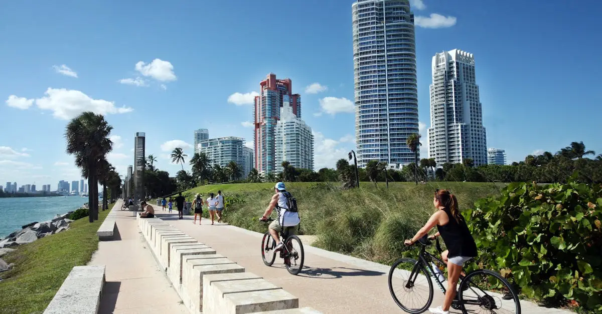 Cyclists ride along a scenic path in Miami Beach, with skyscrapers in the background.