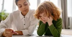 A child and a woman engaged in a music lesson, focusing on reading music sheets indoors.
