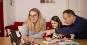 A family learning together with a laptop at home, emphasizing collaboration and education.
